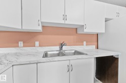 Kitchen featuring white cabinets, light countertops, and freestanding refrigerator - 