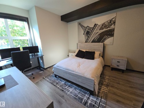 Bedroom with an office area and dark wood-style flooring - 106 10531 117 Street, Edmonton, AB - Indoor Photo Showing Bedroom