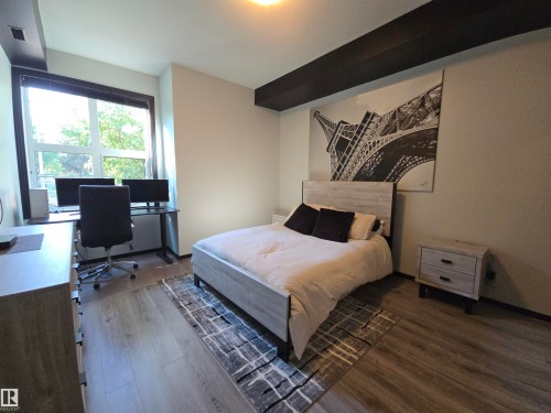 Bedroom featuring an office area and dark wood-style floors - 106 10531 117 Street, Edmonton, AB - Indoor Photo Showing Bedroom