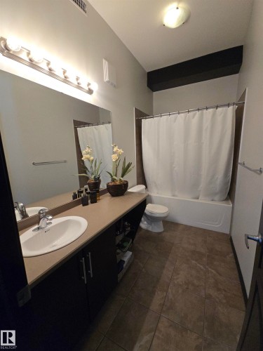 Bathroom featuring vanity, shower / bath combo with shower curtain, and dark tile patterned floors - 106 10531 117 Street, Edmonton, AB - Indoor Photo Showing Bathroom