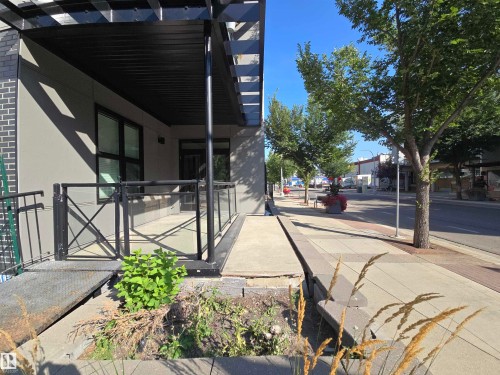 Doorway to property featuring a pergola, brick siding, and stucco siding - 106 10531 117 Street, Edmonton, AB - Outdoor