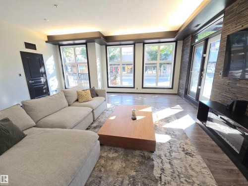 Living area with wood finished floors - 106 10531 117 Street, Edmonton, AB - Indoor Photo Showing Living Room With Fireplace