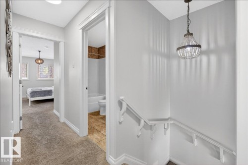 Corridor with light carpet, light tile patterned floors, and an upstairs landing - 12761 119 St, Edmonton, AB - Indoor