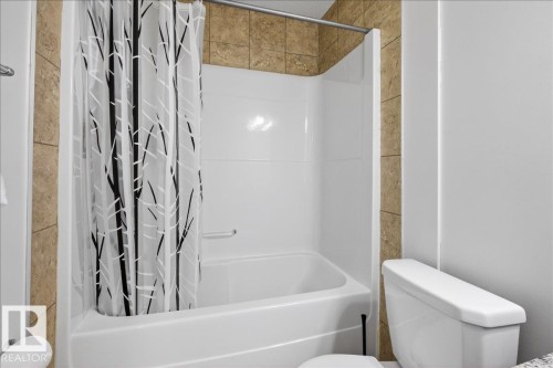 Bathroom featuring toilet and shower / bathtub combination with curtain - 12761 119 St, Edmonton, AB - Indoor Photo Showing Bathroom