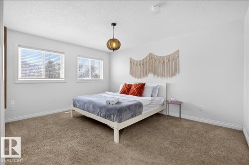 Carpeted bedroom with a textured ceiling and baseboards - 12761 119 St, Edmonton, AB - Indoor Photo Showing Bedroom
