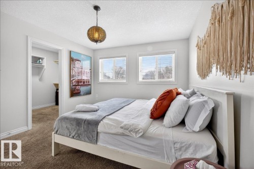 Carpeted bedroom featuring a walk in closet and a textured ceiling - 12761 119 St, Edmonton, AB - Indoor Photo Showing Bedroom