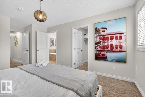Bedroom with a spacious closet, light colored carpet, and a textured ceiling - 12761 119 St, Edmonton, AB - Indoor Photo Showing Bedroom