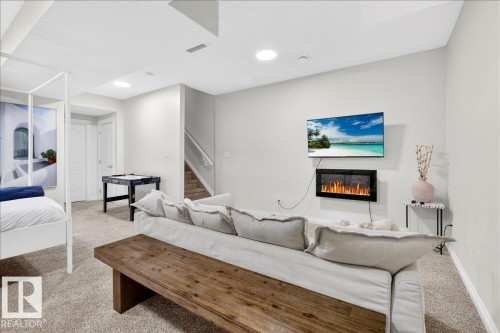 Living room featuring light colored carpet and a glass covered fireplace - 12761 119 St, Edmonton, AB - Indoor With Fireplace