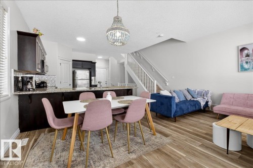 Dining space with a textured ceiling, light wood-style flooring, a chandelier, and arched walkways - 12761 119 St, Edmonton, AB - Indoor