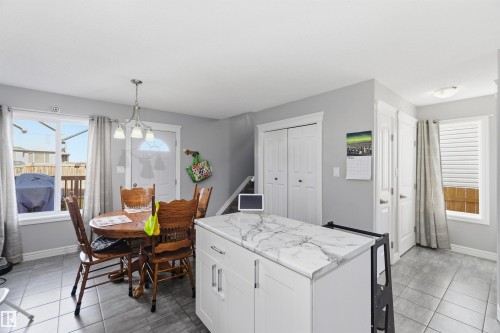 Kitchen with white cabinets, decorative light fixtures, a kitchen island, and light tile patterned flooring - 3908 161 Avenue Nw, Edmonton, AB - Indoor Photo Showing Dining Room