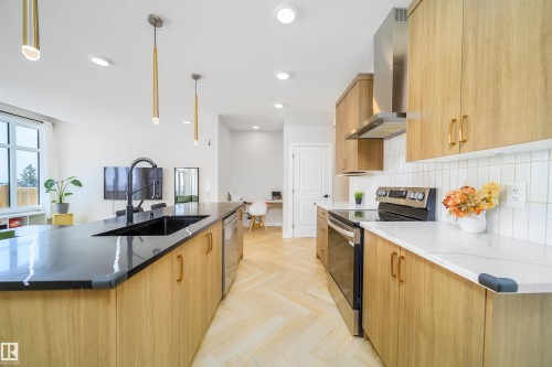 Kitchen with modern cabinets, stainless steel appliances, a spacious island, parquet floors, and dark stone countertops - 15 Chambery Crescent, St. Albert, AB - Indoor Photo Showing Kitchen With Upgraded Kitchen