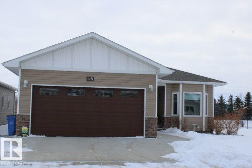 View of front of property featuring stone siding, an attached garage, and board and batten siding - 22 6519 46 Street, Wetaskiwin, AB - Outdoor