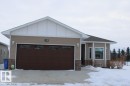 View of front of property featuring stone siding, an attached garage, and board and batten siding - 22 6519 46 Street, Wetaskiwin, AB  - Outdoor 