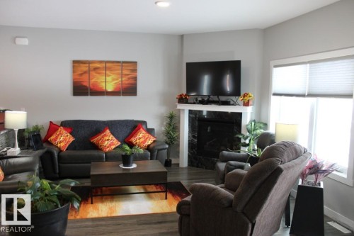 Living area featuring wood finished floors and a premium fireplace - 22 6519 46 Street, Wetaskiwin, AB - Indoor Photo Showing Living Room With Fireplace