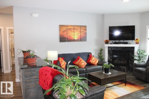 Living room with dark wood-type flooring and a high end fireplace - 22 6519 46 Street, Wetaskiwin, AB - Indoor Photo Showing Living Room With Fireplace