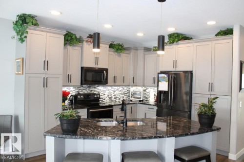 Kitchen with a kitchen bar, black appliances, dark stone counters, and pendant lighting - 22 6519 46 Street, Wetaskiwin, AB - Indoor Photo Showing Kitchen With Upgraded Kitchen