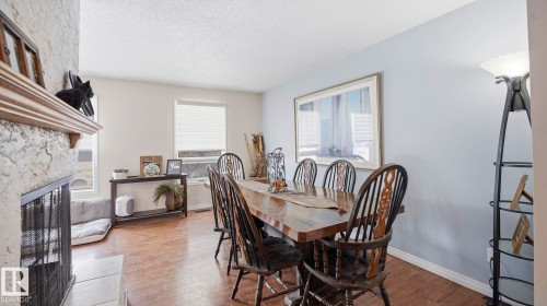 Dining room with a fireplace, hardwood / wood-style flooring, and a textured ceiling - 4502 50A Avenue, Beaumont, AB - Indoor Photo Showing Dining Room With Fireplace