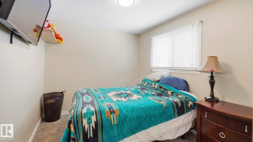 Carpeted bedroom featuring baseboards and a textured ceiling - 4502 50A Avenue, Beaumont, AB - Indoor Photo Showing Bedroom