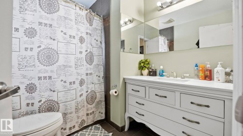 Full bathroom featuring vanity, curtained shower, and dark tile patterned floors - 4502 50A Avenue, Beaumont, AB - Indoor Photo Showing Bathroom