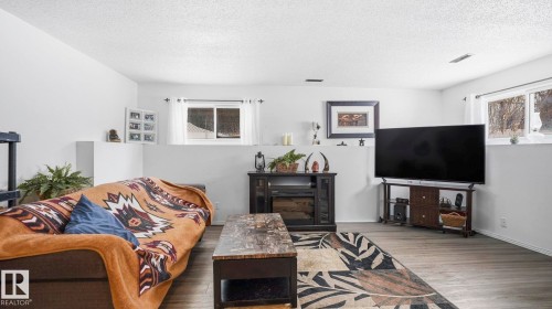 Living room with wood finished floors, a textured ceiling, and plenty of natural light - 4502 50A Avenue, Beaumont, AB - Indoor Photo Showing Living Room