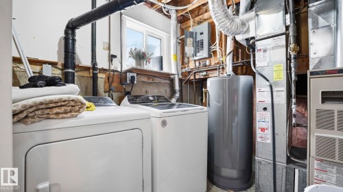 Utility room featuring water heater, electric panel, and washing machine and dryer - 4502 50A Avenue, Beaumont, AB - Indoor