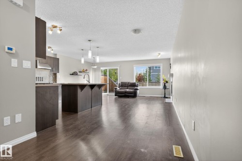 Kitchen with a breakfast bar, light countertops, dark brown cabinets, a textured ceiling, and pendant lighting - 1717 Chapman Way, Edmonton, AB - Indoor
