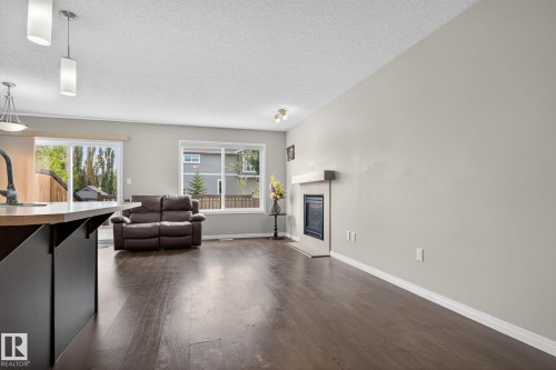 Living room with dark wood finished floors, a textured ceiling, and a glass covered fireplace - 1717 Chapman Way, Edmonton, AB - Indoor Photo Showing Other Room
