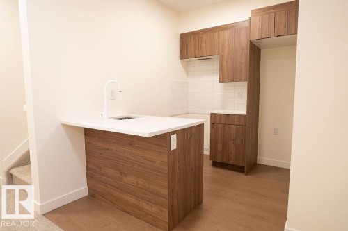 Kitchen with wood finish cabinetry, modern cabinets, light wood-style flooring, and a peninsula - 11738 91 Street Nw, Edmonton, AB - Indoor