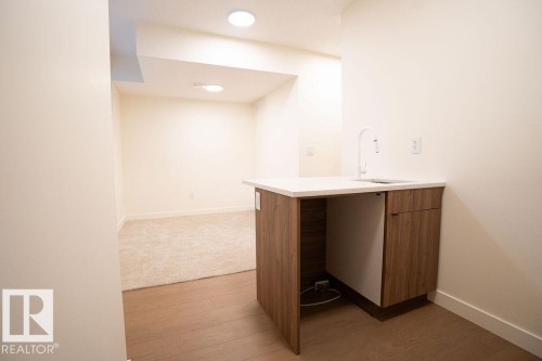 Bar featuring modern cabinets, wood finish cabinetry, light wood-style floors, and light stone countertops - 11738 91 Street Nw, Edmonton, AB - Indoor Photo Showing Other Room