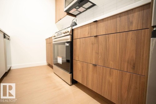 Kitchen with modern cabinets, light wood-type flooring, and white dishwasher - 11738 91 Street Nw, Edmonton, AB - Indoor