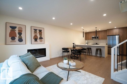 Living room featuring light wood-type flooring, a glass covered fireplace, and recessed lighting - 11738 91 Street Nw, Edmonton, AB - Indoor With Fireplace