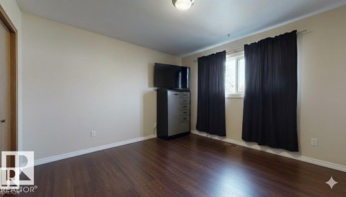 Unfurnished bedroom with wood finished floors and baseboards - 4706 53 St, Leduc, AB - Indoor Photo Showing Other Room