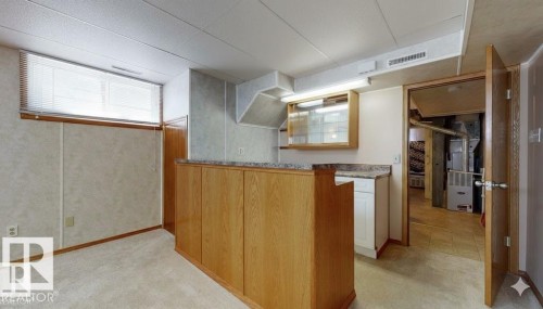 Kitchen featuring light colored carpet, heating unit, and wood finish cabinetry - 4706 53 St, Leduc, AB - Indoor Photo Showing Other Room