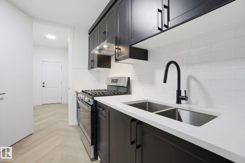 Kitchen with stainless steel gas range, parquet floors, light stone counters, dark cabinetry, and recessed lighting - 3294 Chernowski Way, Edmonton, AB - Indoor Photo Showing Kitchen With Double Sink With Upgraded Kitchen