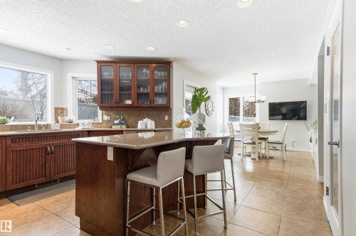 Kitchen with backsplash, a kitchen breakfast bar, glass insert cabinets, a center island, and decorative light fixtures - 326 O'Connor Close, Edmonton, AB - Indoor