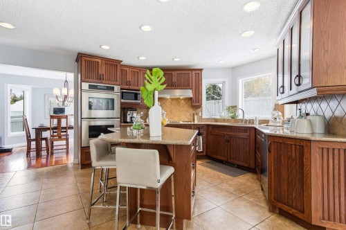 Kitchen featuring a kitchen island, stainless steel appliances, light stone counters, a breakfast bar area, and recessed lighting - 326 O'Connor Close, Edmonton, AB - Indoor
