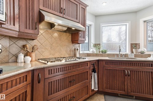 Kitchen featuring healthy amount of natural light, light stone countertops, a textured ceiling, stainless steel gas stovetop, and decorative backsplash - 326 O'Connor Close, Edmonton, AB - Indoor Photo Showing Kitchen