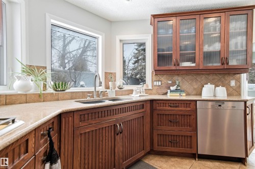 Kitchen with dishwasher, light stone counters, glass fronted cabinets, and wood finish cabinets - 326 O'Connor Close, Edmonton, AB - Indoor Photo Showing Kitchen