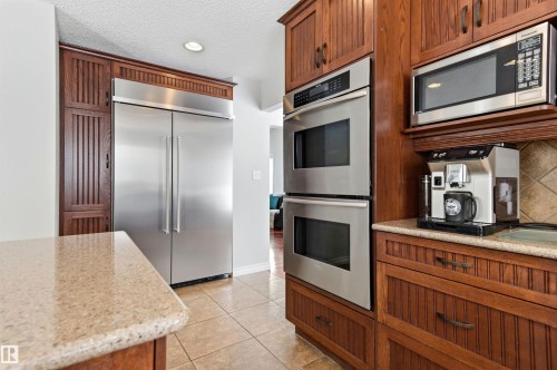 Kitchen with stainless steel appliances, wood finish cabinetry, light stone countertops, light tile patterned flooring, and decorative backsplash - 326 O'Connor Close, Edmonton, AB - Indoor Photo Showing Kitchen