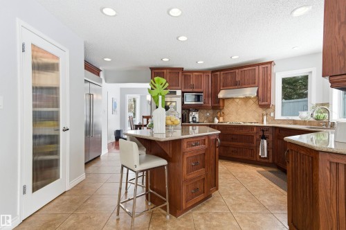Kitchen with light stone counters, light tile patterned flooring, a kitchen bar, recessed lighting, and a kitchen island - 326 O'Connor Close, Edmonton, AB - Indoor Photo Showing Kitchen With Upgraded Kitchen