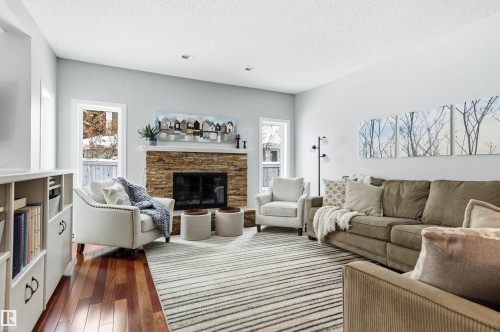 Living area featuring dark wood finished floors, a fireplace, plenty of natural light, and a textured ceiling - 326 O'Connor Close, Edmonton, AB - Indoor Photo Showing Living Room With Fireplace