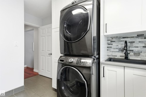 Laundry room with tile patterned flooring, stacked washer and dryer, and cabinet space - 326 O'Connor Close, Edmonton, AB - Indoor Photo Showing Laundry Room