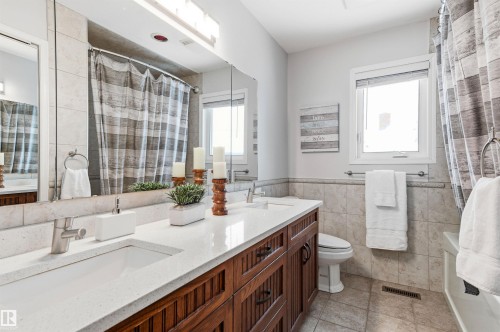 Bathroom with double vanity, tile walls, wainscoting, a shower with shower curtain, and light tile patterned floors - 326 O'Connor Close, Edmonton, AB - Indoor Photo Showing Bathroom