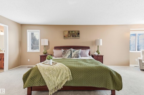 Bedroom featuring carpet, ensuite bathroom, multiple windows, and a textured ceiling - 326 O'Connor Close, Edmonton, AB - Indoor Photo Showing Bedroom
