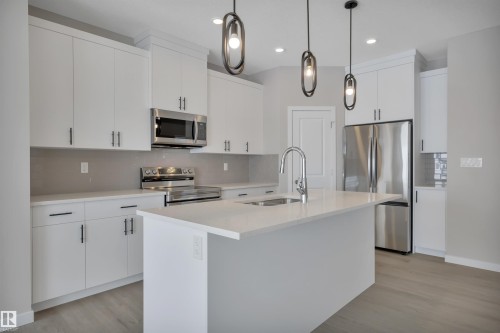 Kitchen with stainless steel appliances, backsplash, a kitchen island with sink, and white cabinetry - 5657 Hawthorn Way, Edmonton, AB - Indoor Photo Showing Kitchen With Stainless Steel Kitchen With Double Sink With Upgraded Kitchen