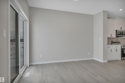 Kitchen with stainless steel appliances, white cabinets, light countertops, light wood-style floors, and backsplash - 5657 Hawthorn Way, Edmonton, AB - Indoor Photo Showing Kitchen