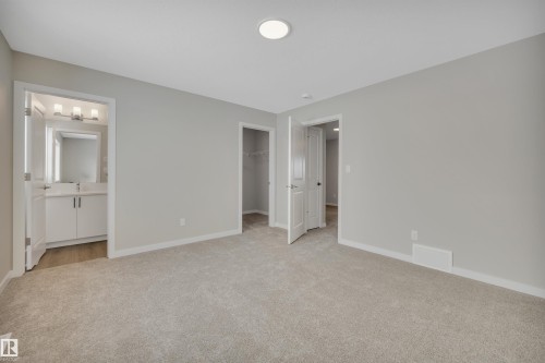 Unfurnished bedroom featuring a spacious closet, light carpet, and ensuite bath - 5657 Hawthorn Way, Edmonton, AB - Indoor Photo Showing Other Room