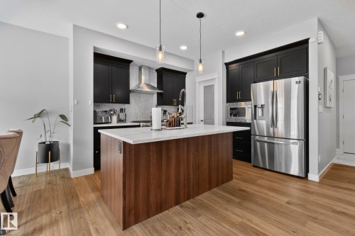 Kitchen featuring stainless steel appliances, pendant lighting, a center island with sink, light stone countertops, and light wood-type flooring - 324 41 Street, Edmonton, AB - Indoor Photo Showing Kitchen With Upgraded Kitchen