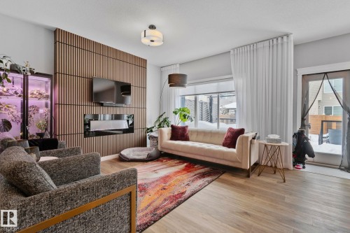 Living area featuring light wood-style flooring, plenty of natural light, and a glass covered fireplace - 324 41 Street, Edmonton, AB - Indoor Photo Showing Living Room