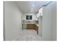 Kitchen featuring modern cabinets, brown cabinetry, white cabinetry, light marble finish floors, and recessed lighting - 